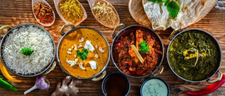 Photo for Composition with indian dishes: madras paneer, palak paneer and shahi paneer with basmati rice served in original indian karahi pots - Royalty Free Image