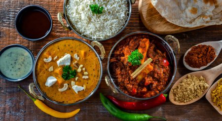 Foto de Composición con platos indios: madras paneer, palak paneer y shahi paneer con arroz basmati servido en macetas karahi indias originales - Imagen libre de derechos