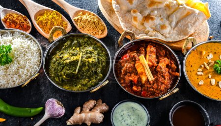 Foto de Composición con platos indios: madras paneer, palak paneer y shahi paneer con arroz basmati servido en macetas karahi indias originales - Imagen libre de derechos