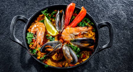 Téléchargez les photos : Paella aux fruits de mer servie dans une casserole en fonte. - en image libre de droit