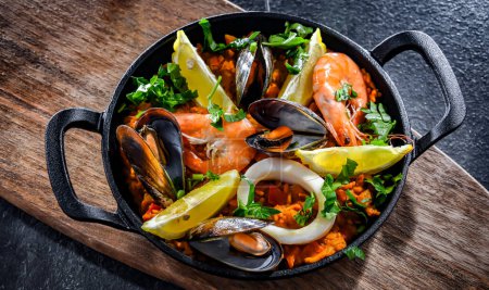 Téléchargez les photos : Paella aux fruits de mer servie dans une casserole en fonte. - en image libre de droit