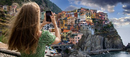 Téléchargez les photos : Une touriste prenant une photo du village de Manarola à Cinque Terre, Ligurie, Italie - en image libre de droit