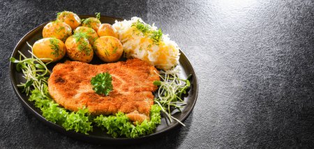 Foto de Pork breaded cutlet coated with breadcrumbs served with potatoes and cabbage - Imagen libre de derechos