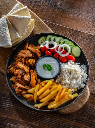 Téléchargez les photos : Kebab servi avec riz, frites, pain pitta, légumes et tzatziki - en image libre de droit