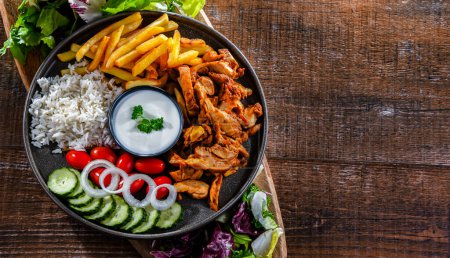 Photo for Kebab served with rice, french fries, pitta bread, vegetables and tzatziki - Royalty Free Image