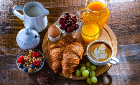 Photo for Breakfast served with coffee, orange juice, egg, cereals and croissants. - Royalty Free Image
