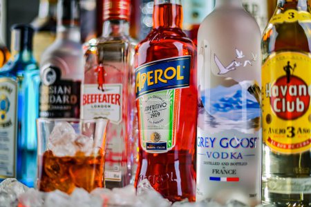 Téléchargez les photos : POZNAN, POL - 29 NOV 2023 : Verre de boisson alcoolisée sur des bouteilles de marques mondiales de liqueurs dures dans un bar - en image libre de droit