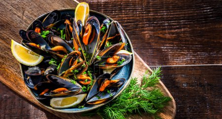Photo for Composition with a plate of steamed mussels served with parsley and lemon - Royalty Free Image