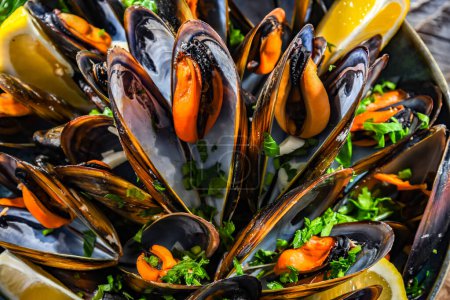 Photo for Composition with a plate of steamed mussels served with parsley and lemon - Royalty Free Image