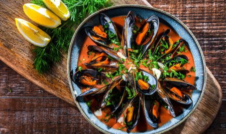 Photo for A plate of mussels in tomato sauce served with parsley and lemon - Royalty Free Image