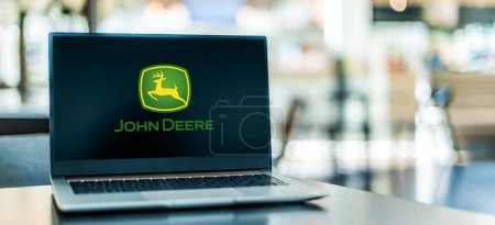 Foto de POZNAN, POL - 6 ENE 2024: Computadora portátil que muestra el logotipo de John Deere, una corporación que fabrica maquinaria agrícola, equipos pesados, maquinaria forestal, etc. - Imagen libre de derechos