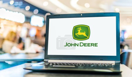 Foto de POZNAN, POL - 6 ENE 2024: Computadora portátil que muestra el logotipo de John Deere, una corporación que fabrica maquinaria agrícola, equipos pesados, maquinaria forestal, etc. - Imagen libre de derechos