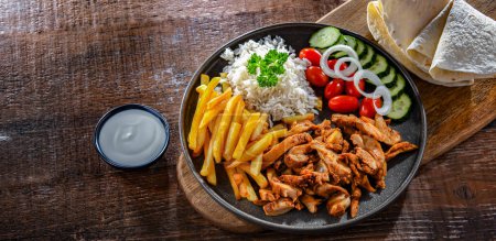Téléchargez les photos : Kebab servi avec riz, frites, pain pitta, légumes et tzatziki - en image libre de droit