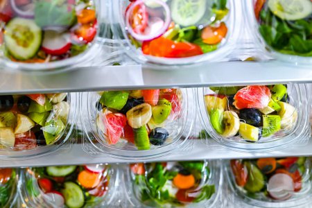 Téléchargez les photos : Boîtes en plastique avec salades de fruits et légumes préemballées, conditionnées pour la vente au réfrigérateur commercial - en image libre de droit