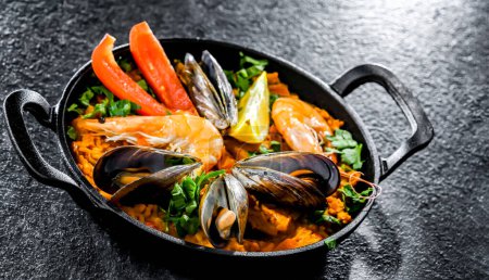Photo for Seafood paella served in a cast iron pan. - Royalty Free Image