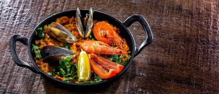 Foto de Seafood paella served in a cast iron pan. - Imagen libre de derechos