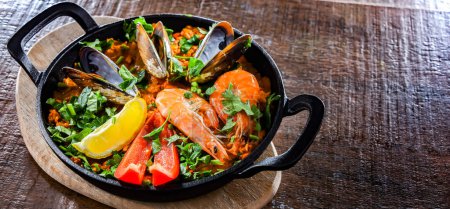 Téléchargez les photos : Seafood paella served in a cast iron pan. - en image libre de droit