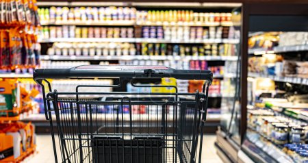 Téléchargez les photos : Un caddie près d'une étagère dans un supermarché - en image libre de droit