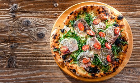 Photo for Pizza Italiana served with ham, cheese, tomatoes and rucola. - Royalty Free Image