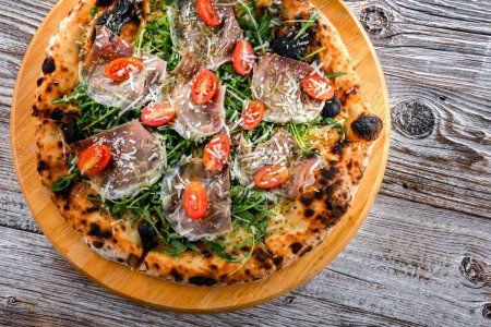 Foto de Pizza Italiana servida con jamón, queso, tomate y rúcula. - Imagen libre de derechos