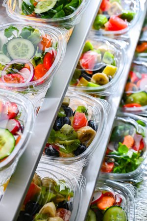 Foto de Plastic boxes with pre-packaged fruit and vegetable salads, put up for sale in a commercial refrigerator - Imagen libre de derechos