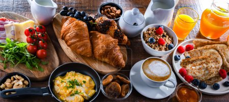 Téléchargez les photos : Breakfast served with coffee, orange juice, scrambled eggs, cereals, pancakes and croissants. - en image libre de droit