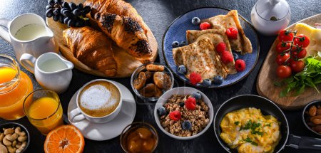 Photo for Breakfast served with coffee, orange juice, scrambled eggs, cereals, pancakes and croissants. - Royalty Free Image