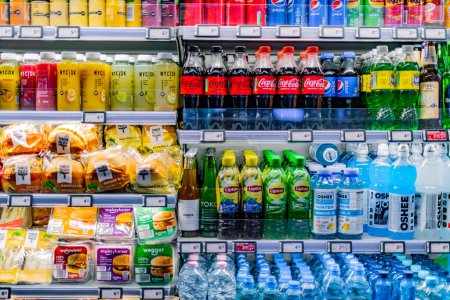 Foto de POZNAN, POL - 12 MAR 2022: Alimentos y bebidas preenvasados que se muestran en un refrigerador comercial en una tienda de conveniencia - Imagen libre de derechos