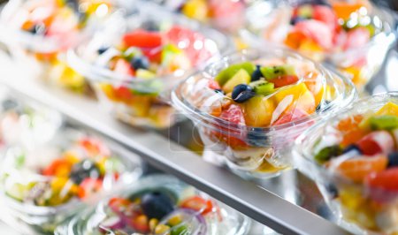 Téléchargez les photos : Plastic boxes with pre-packaged fruit salads, put up for sale in a commercial refrigerator - en image libre de droit