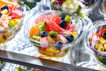 Foto de Plastic boxes with pre-packaged fruit salads, put up for sale in a commercial refrigerator - Imagen libre de derechos