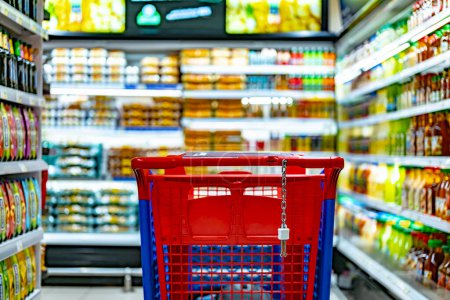 Foto de Un carrito de compras junto a un estante de una tienda en un supermercado - Imagen libre de derechos