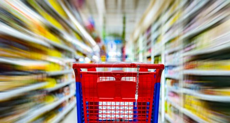 Foto de Un carrito de compras junto a un estante de una tienda en un supermercado - Imagen libre de derechos