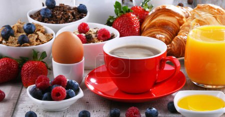 Photo for Breakfast served with coffee, orange juice, croissants, egg, cereals and fruits. Balanced diet. - Royalty Free Image