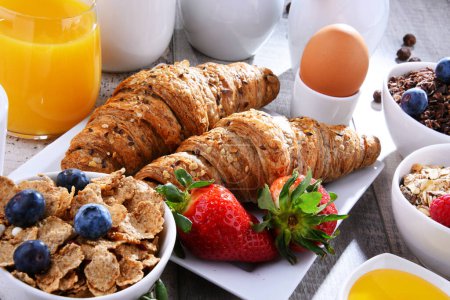 Téléchargez les photos : Petit déjeuner servi avec café, jus d'orange, croissants, œufs, céréales et fruits. Régime alimentaire équilibré. - en image libre de droit