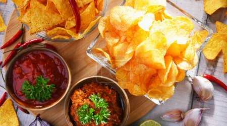 Photo for Composition with glass bowl of potato chips and dipping sauces. - Royalty Free Image