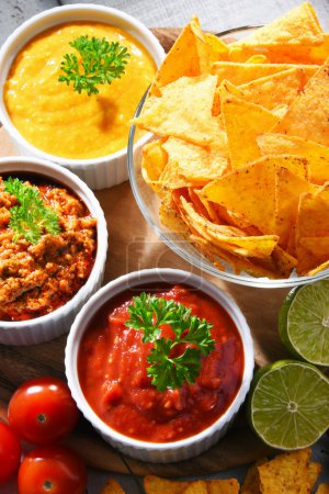 Photo for Composition with glass bowl of tortilla chips and dipping sauces. - Royalty Free Image