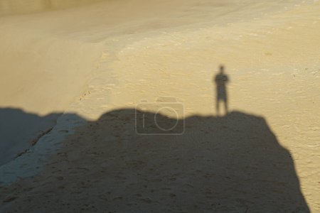 Téléchargez les photos : Ombre d'un homme debout sur un rocher dans le sable. - en image libre de droit