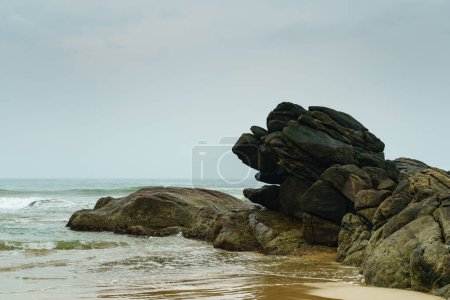 Téléchargez les photos : D'énormes rochers sur le rivage sablonneux de l'océan. - en image libre de droit