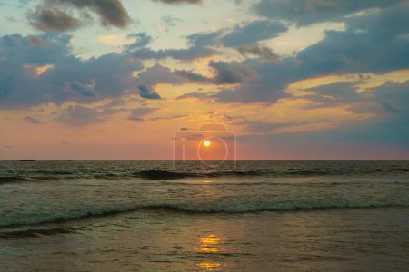 Téléchargez les photos : Le soleil orange se couche sur fond de mer et de nuages. - en image libre de droit