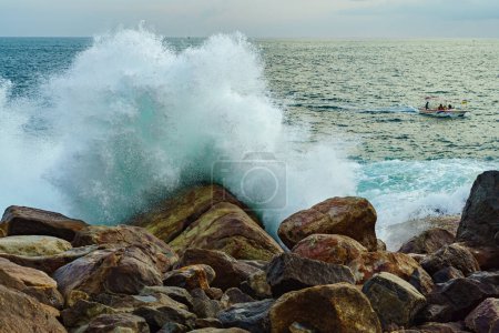 Téléchargez les photos : Paysage marin avec de gros rochers et de hautes vagues et un bateau. - en image libre de droit