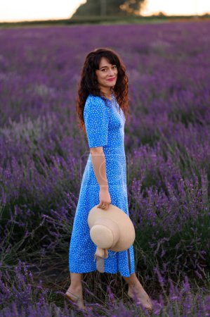 Photo for Portrait of a happy woman in a blue dress enjoying a sunny summer day in a lavender field. Fresh air, Lifestyle. - Royalty Free Image