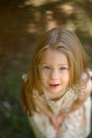 Photo for Little girl 3 years old in a summer sundress in the park. Summer time.Close-up. Taken from above. - Royalty Free Image