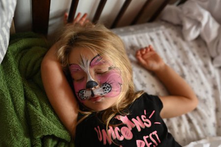 Photo for Little girl 3 years old with a painted face. Baby sleeps in her bed - Royalty Free Image