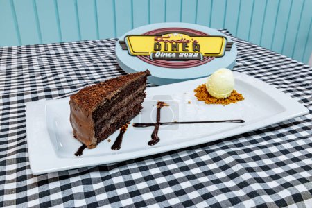 Foto de Composición de un pastel de chocolate en un plato blanco con helado sobre un mantel a cuadros blanco y negro - Imagen libre de derechos