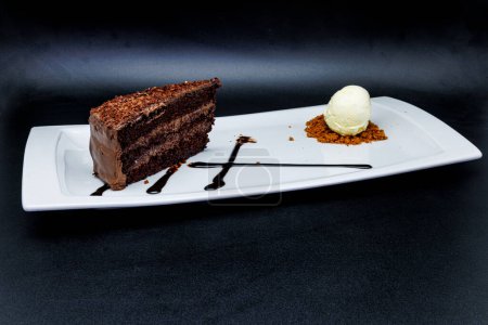 Foto de Composición de un pastel de chocolate en un plato blanco con helado sobre un fondo negro - Imagen libre de derechos