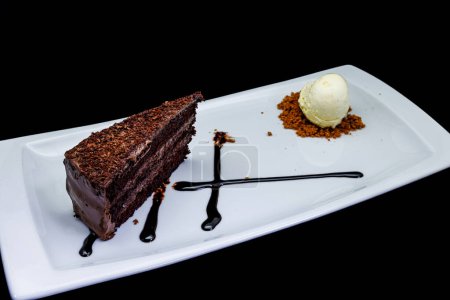 Photo for Composition of a Chocolate cake on a white plate with ice cream on a black background - Royalty Free Image