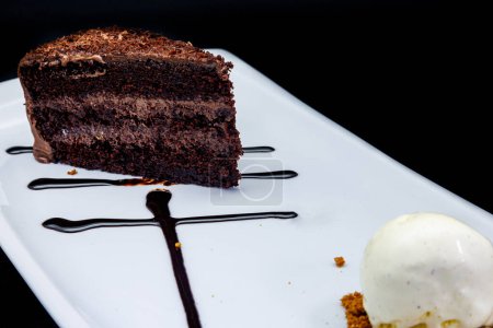 Téléchargez les photos : Composition d'un gâteau au chocolat sur une assiette blanche avec crème glacée sur fond noir - en image libre de droit