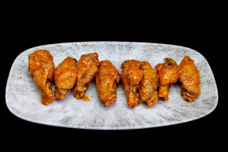 Téléchargez les photos : Composition d'une assiette d'ailes de poulet avec sauce Buffalo sur fond noir. - en image libre de droit