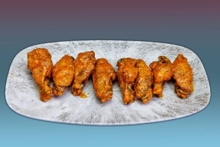 Foto de Composición de un plato de alitas de pollo con salsa Buffalo sobre un fondo magenta y azul claro. - Imagen libre de derechos