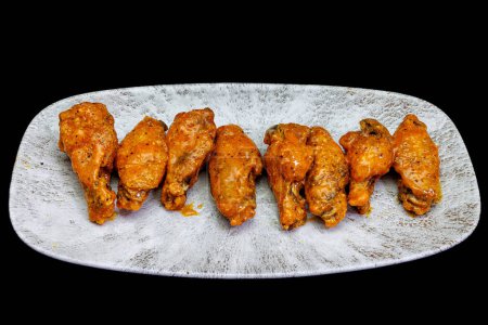 Foto de Composición de un plato de alitas de pollo con salsa Buffalo sobre fondo negro. - Imagen libre de derechos